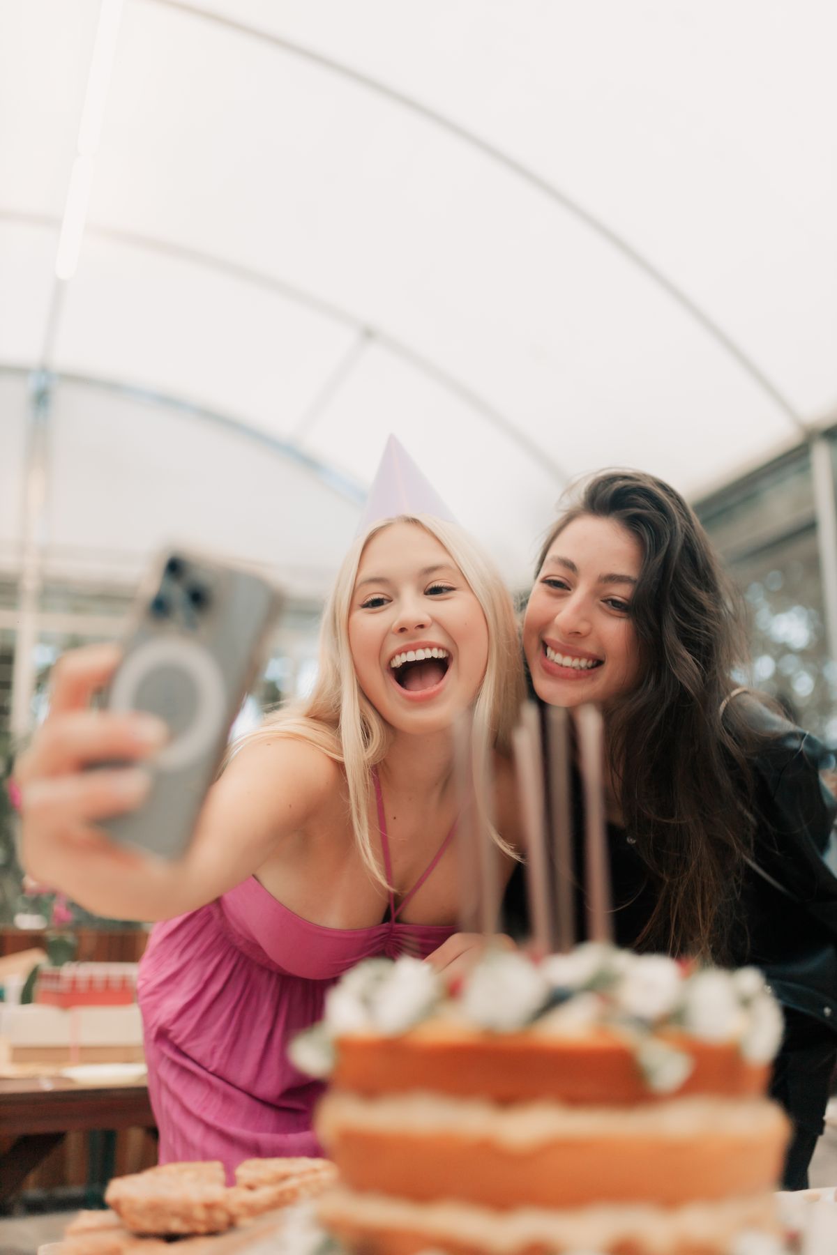 Friends capturing a birthday cake moment on a phone