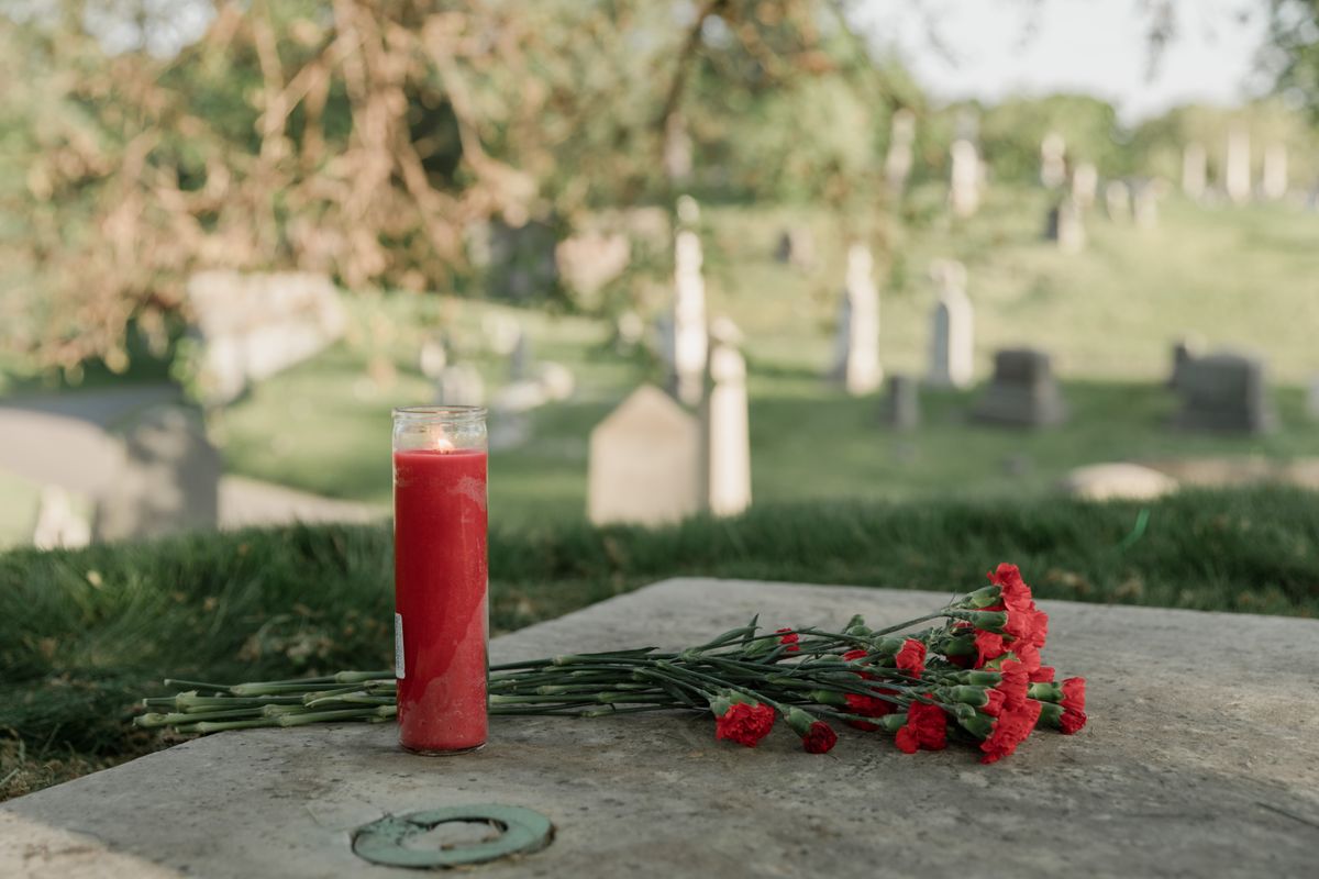 A red candle and flowers placed on a tomb for remembrance